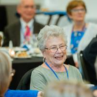 Alumna smiles as she enjoys conversation at her table at the Reunion Dinner.